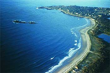 Aerial view of wave refraction pattern in wave fronts as they approach the shore.  Embayment in foreground and headland in background.
